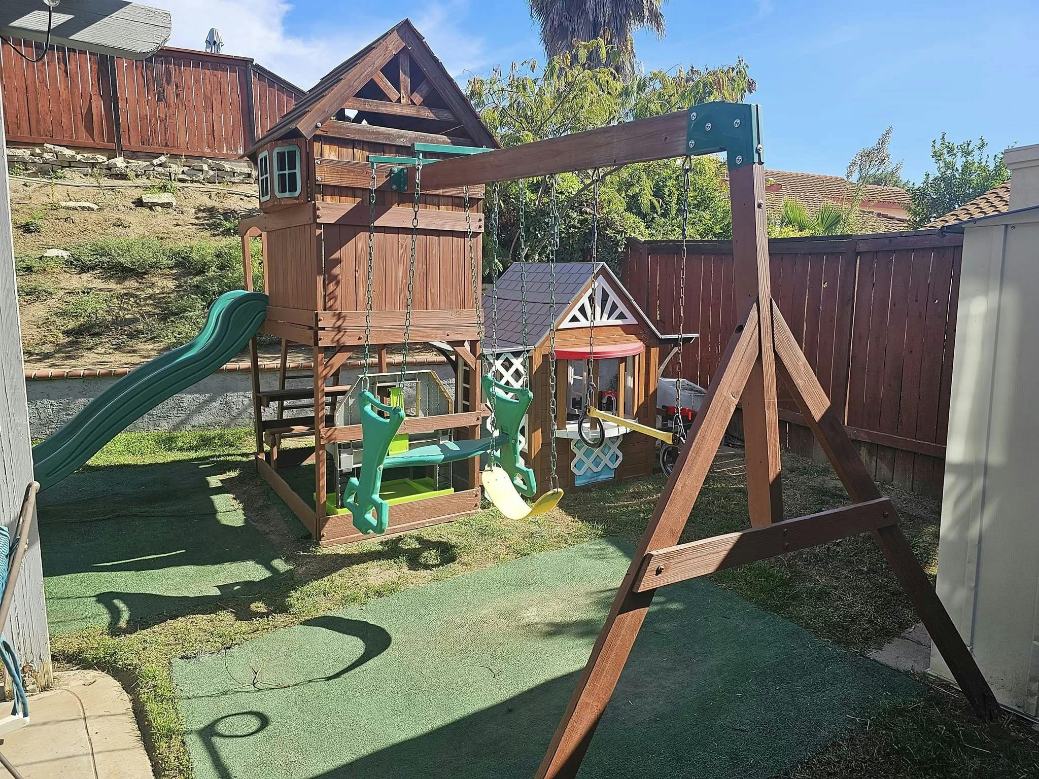 Wooden playset with a slide, swings, and a small playhouse