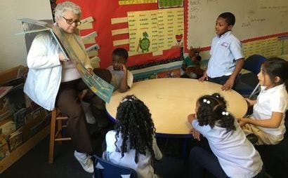 Person reading a book to children in a classroom