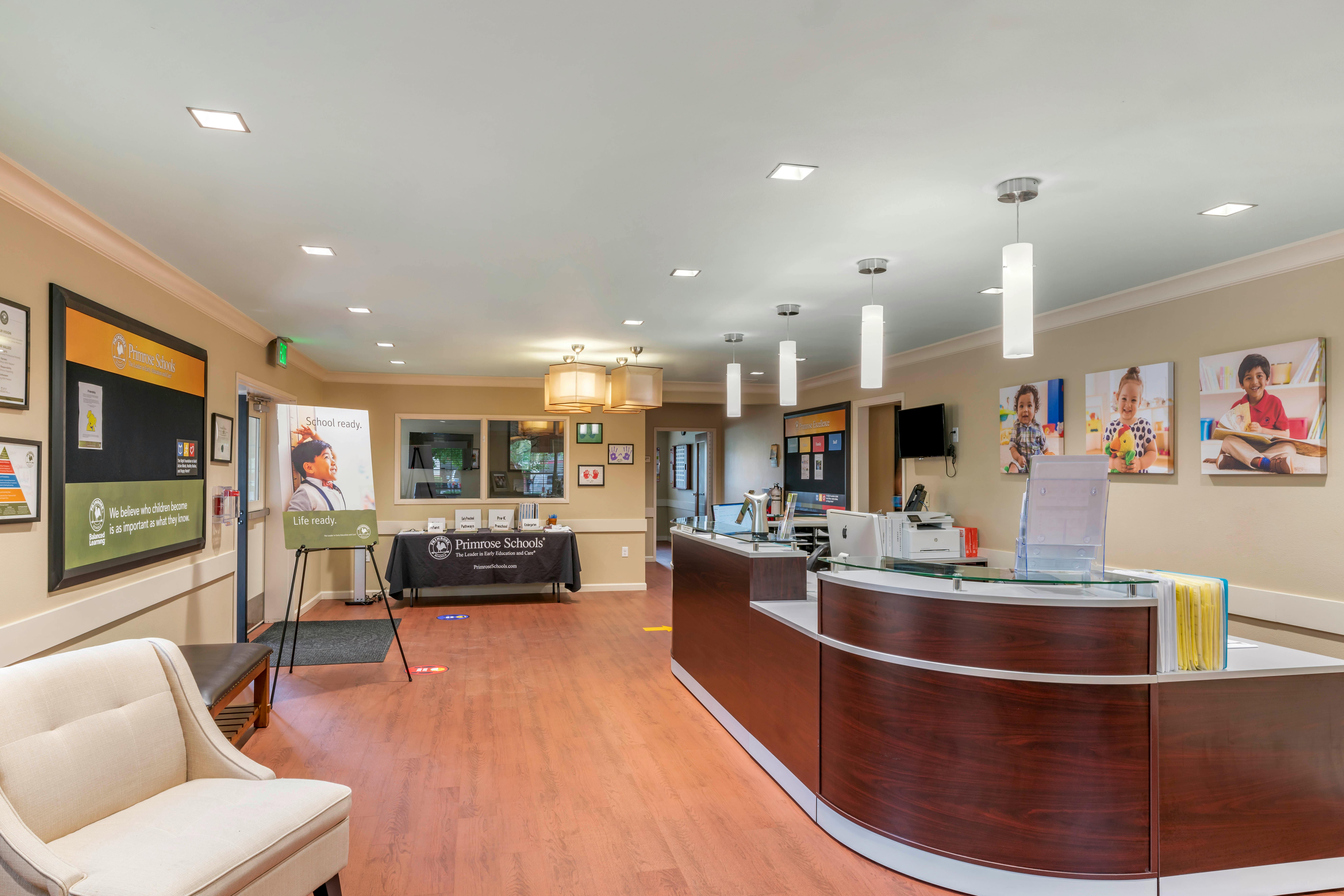 lobby of a school with a reception desk, a bulletin board, and signs