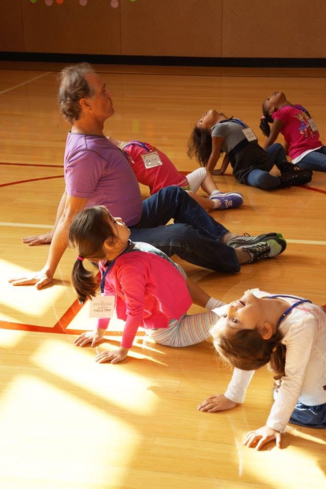 Adult and children stretching on a wooden floor