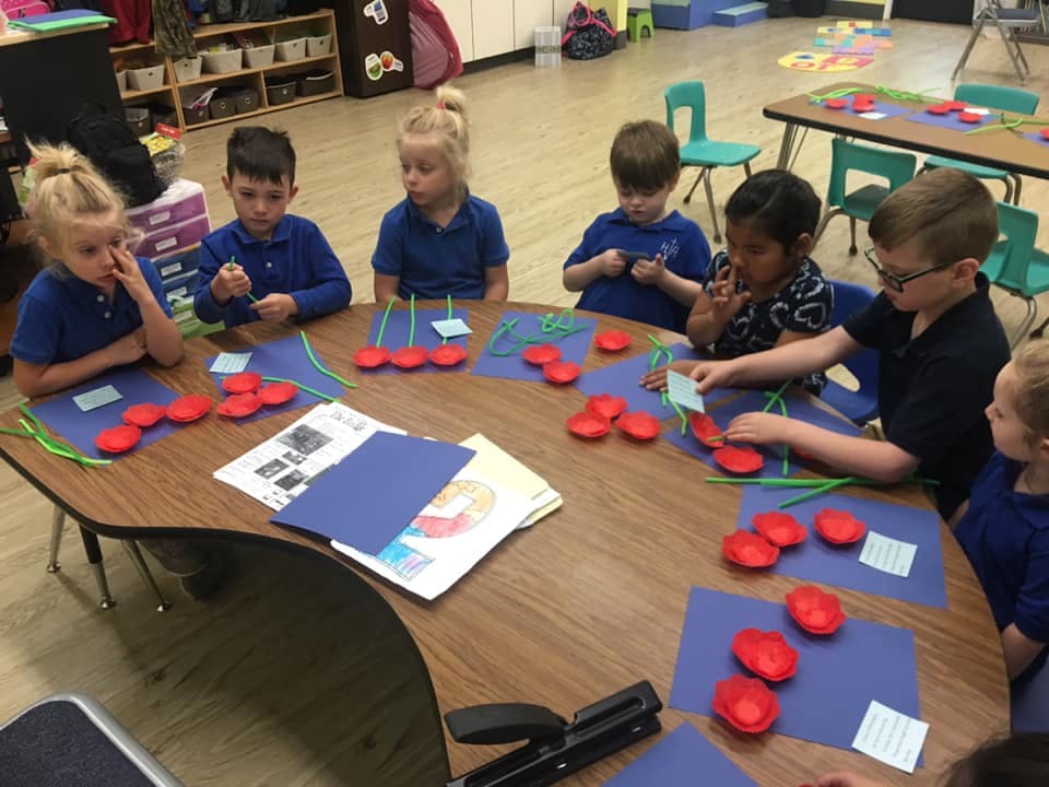 Children at a table with red heart shapes and blue paper