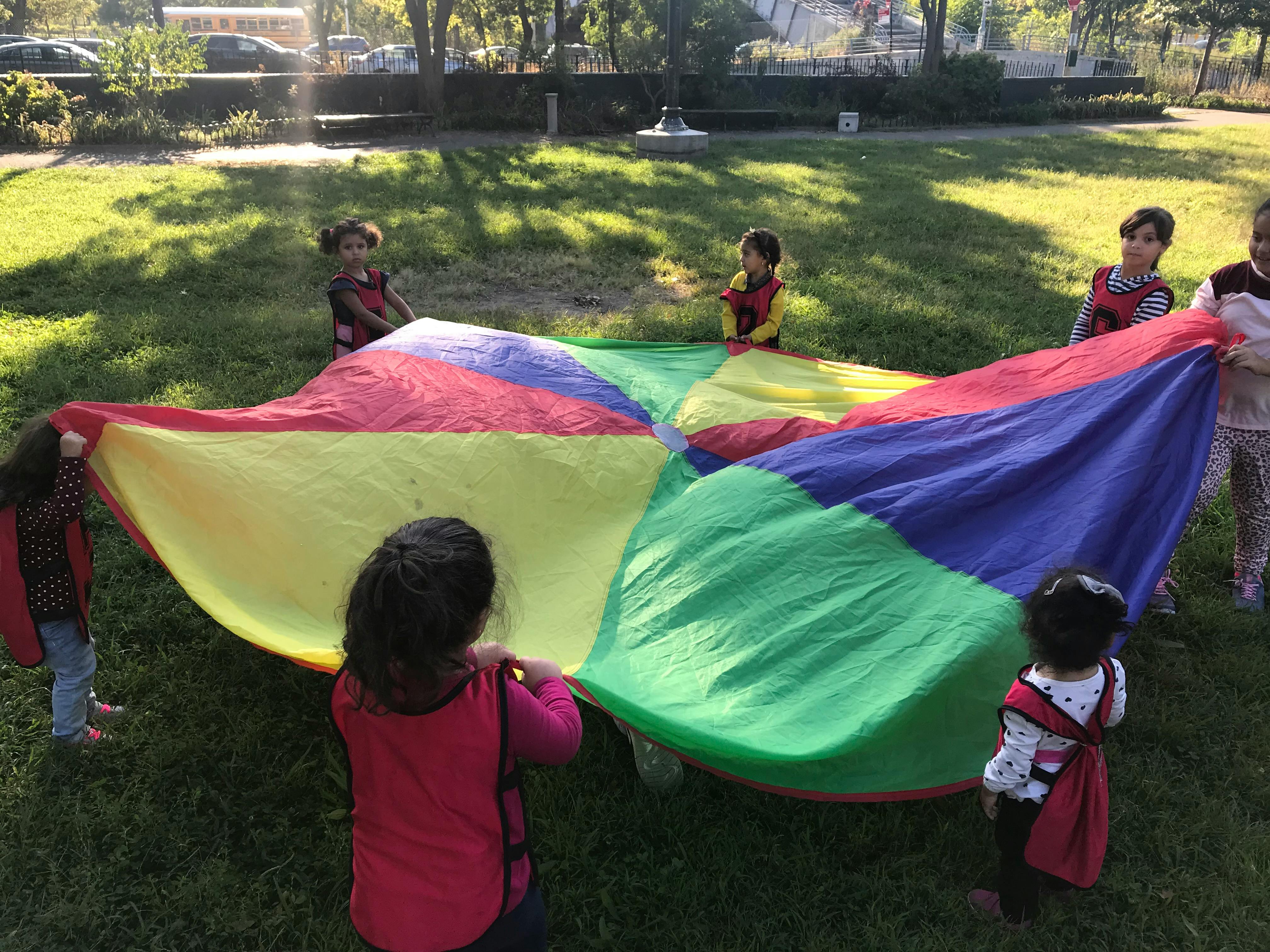 Children playing with a large colorful parachute outdoors