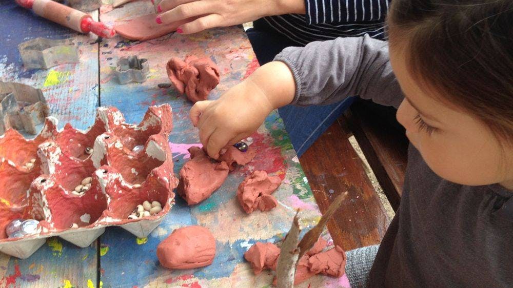 Child playing with clay and an egg carton