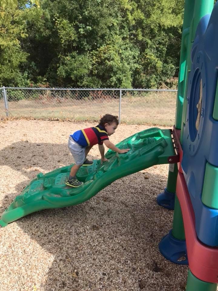 Child climbing a green playground slide