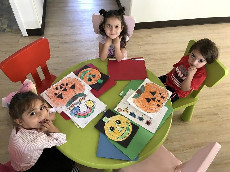Three children sitting around a table with craft projects