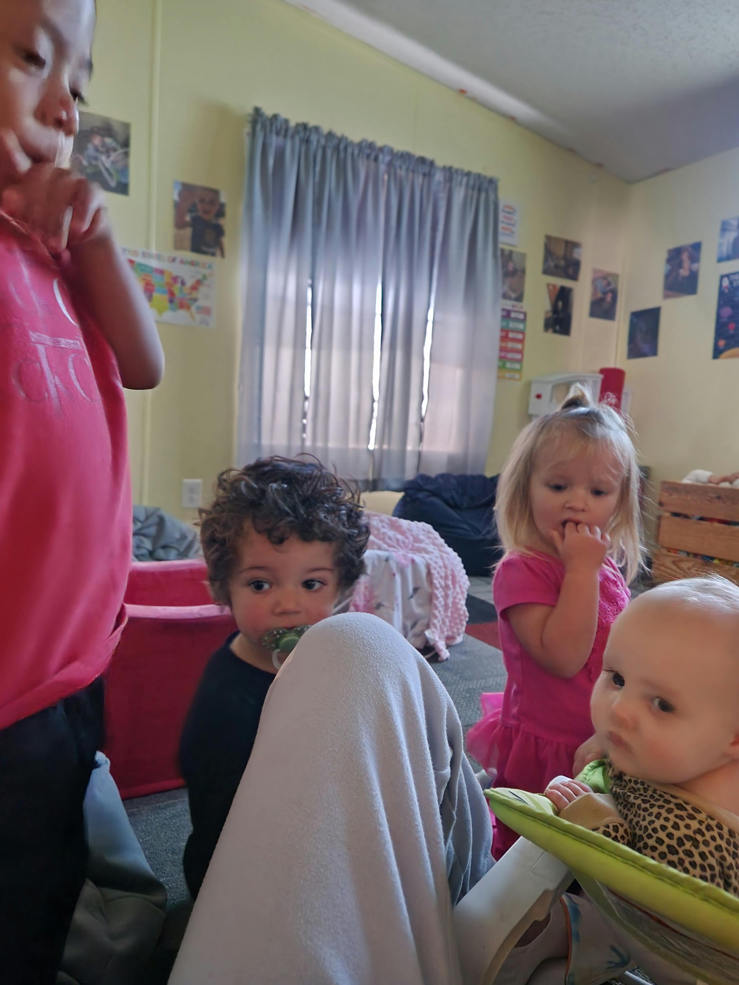 Four children in a room, one in a baby seat