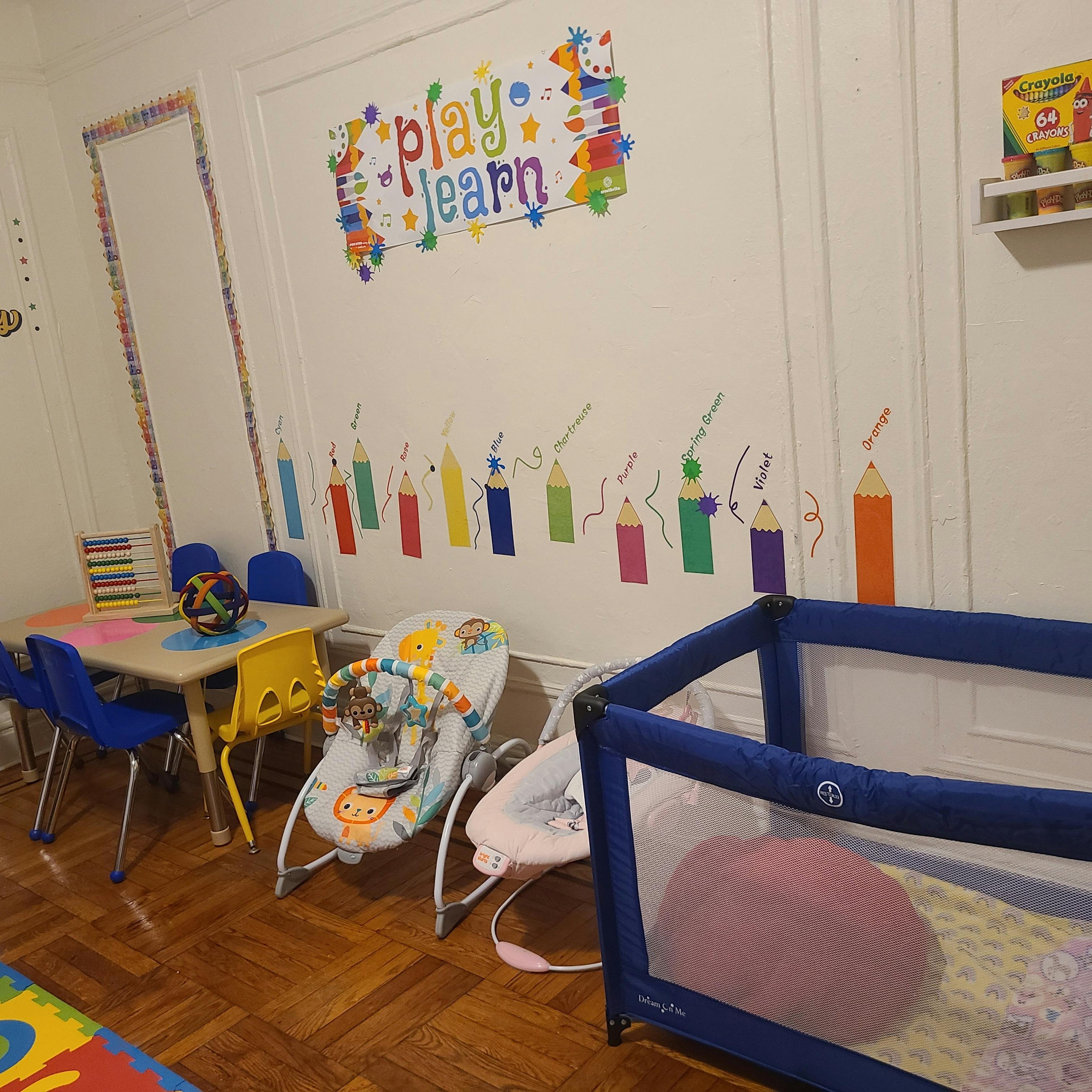 Playroom with a small table and chairs, baby bouncers, and a playpen