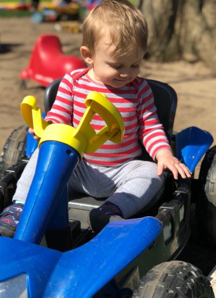 Child in a red and white striped shirt sitting in a toy car