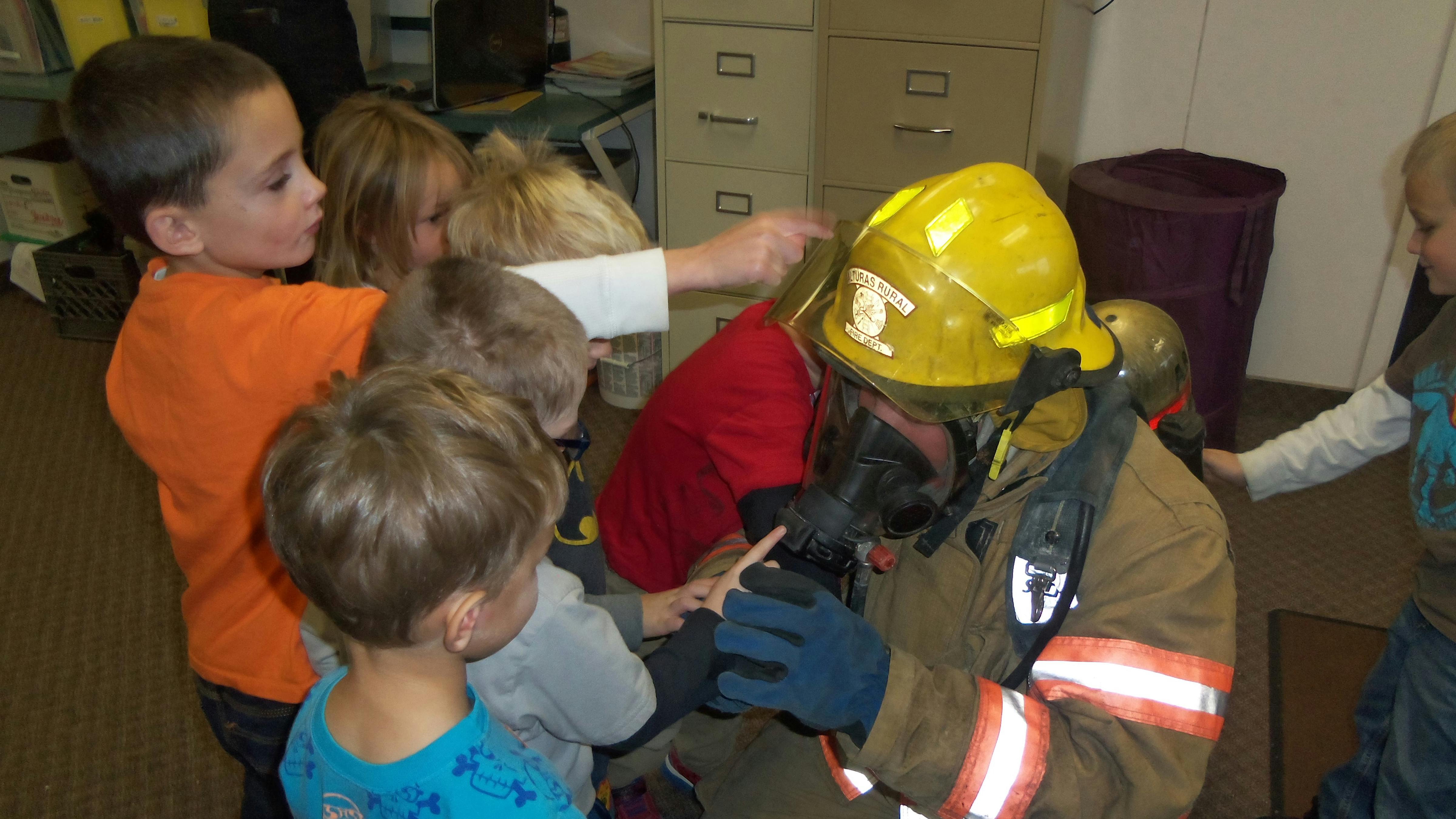 Firefighter in gear interacting with children