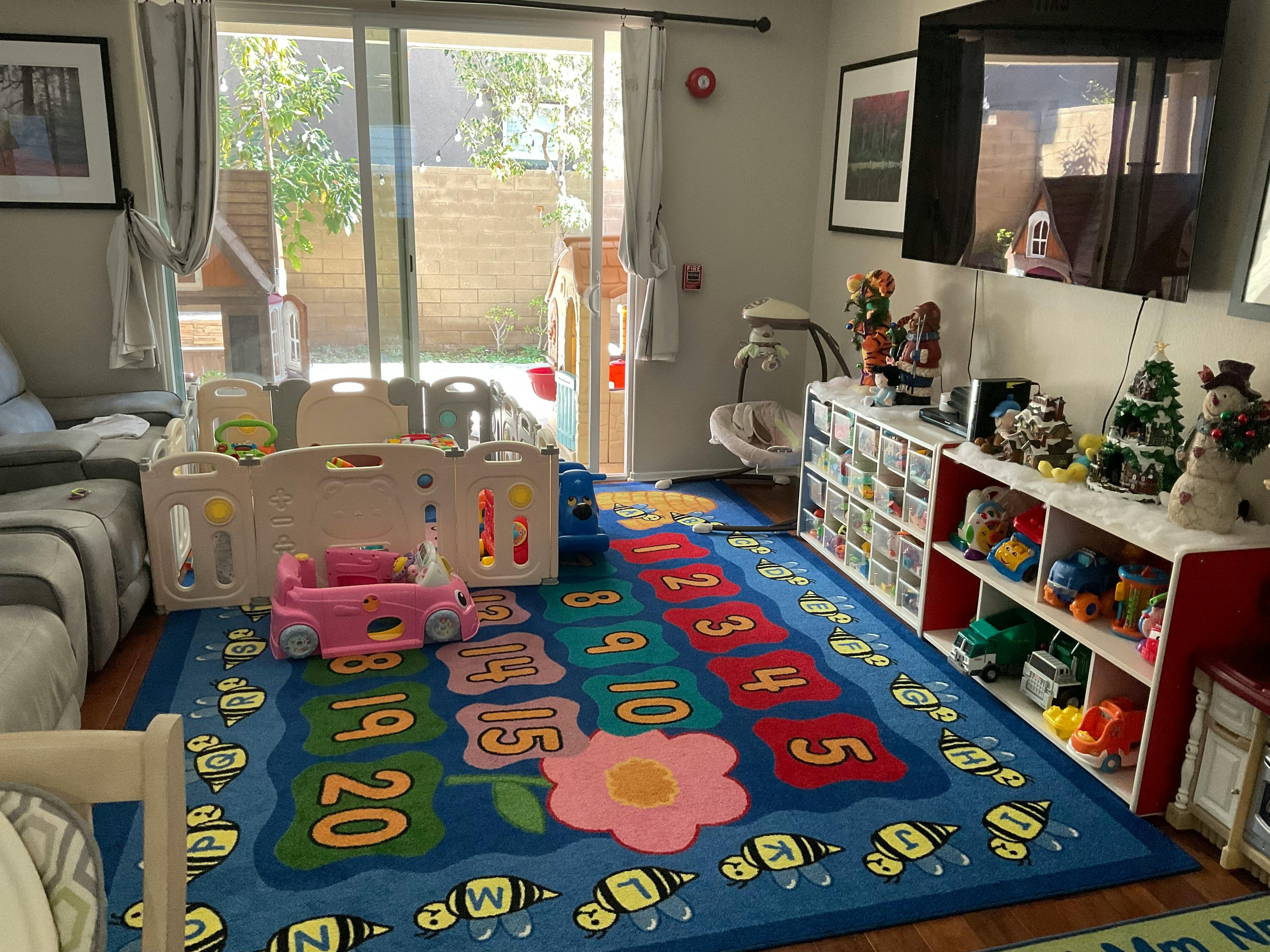 Playroom with a colorful rug, playpen, and toy shelves