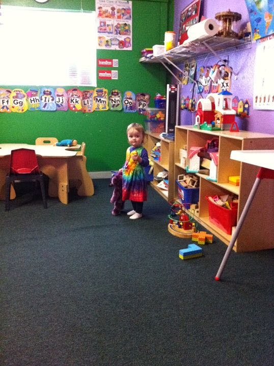 Child holding a stuffed animal in a classroom