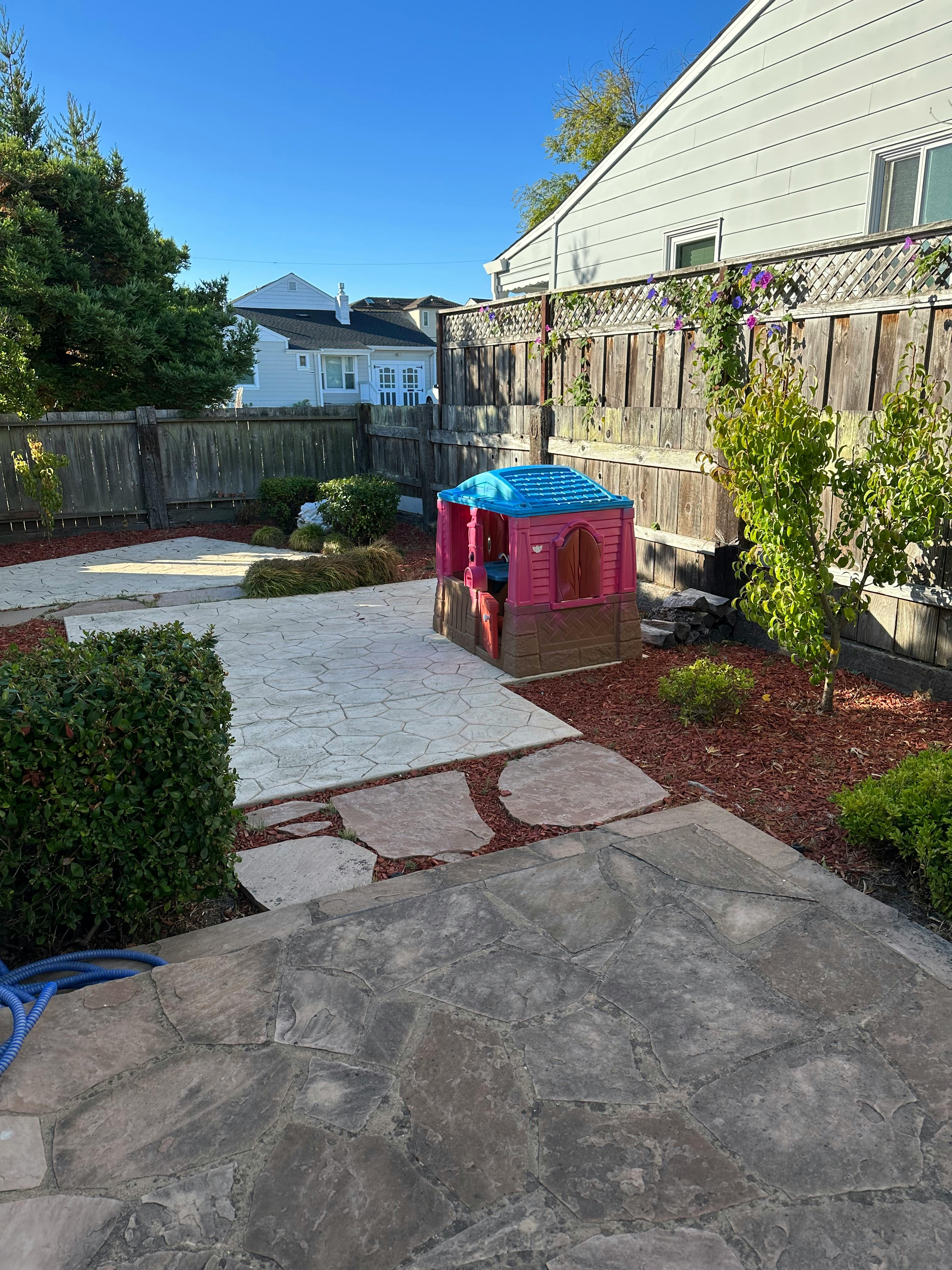 Backyard with a small playhouse and stone patio
