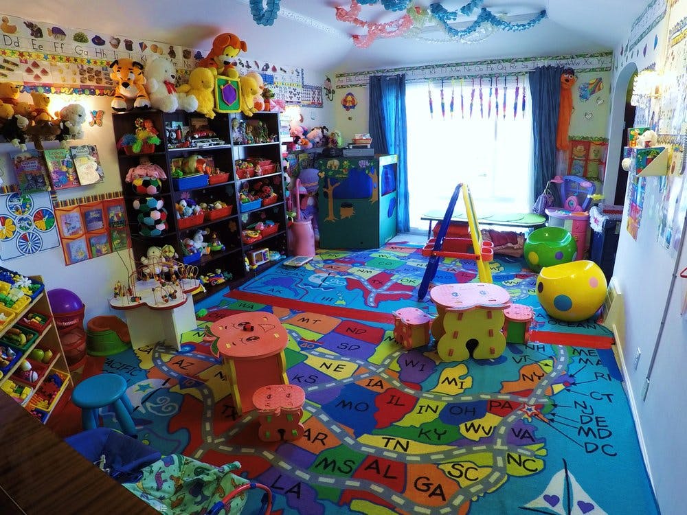 Playroom with a colorful map rug, shelves of toys, and small tables and chairs