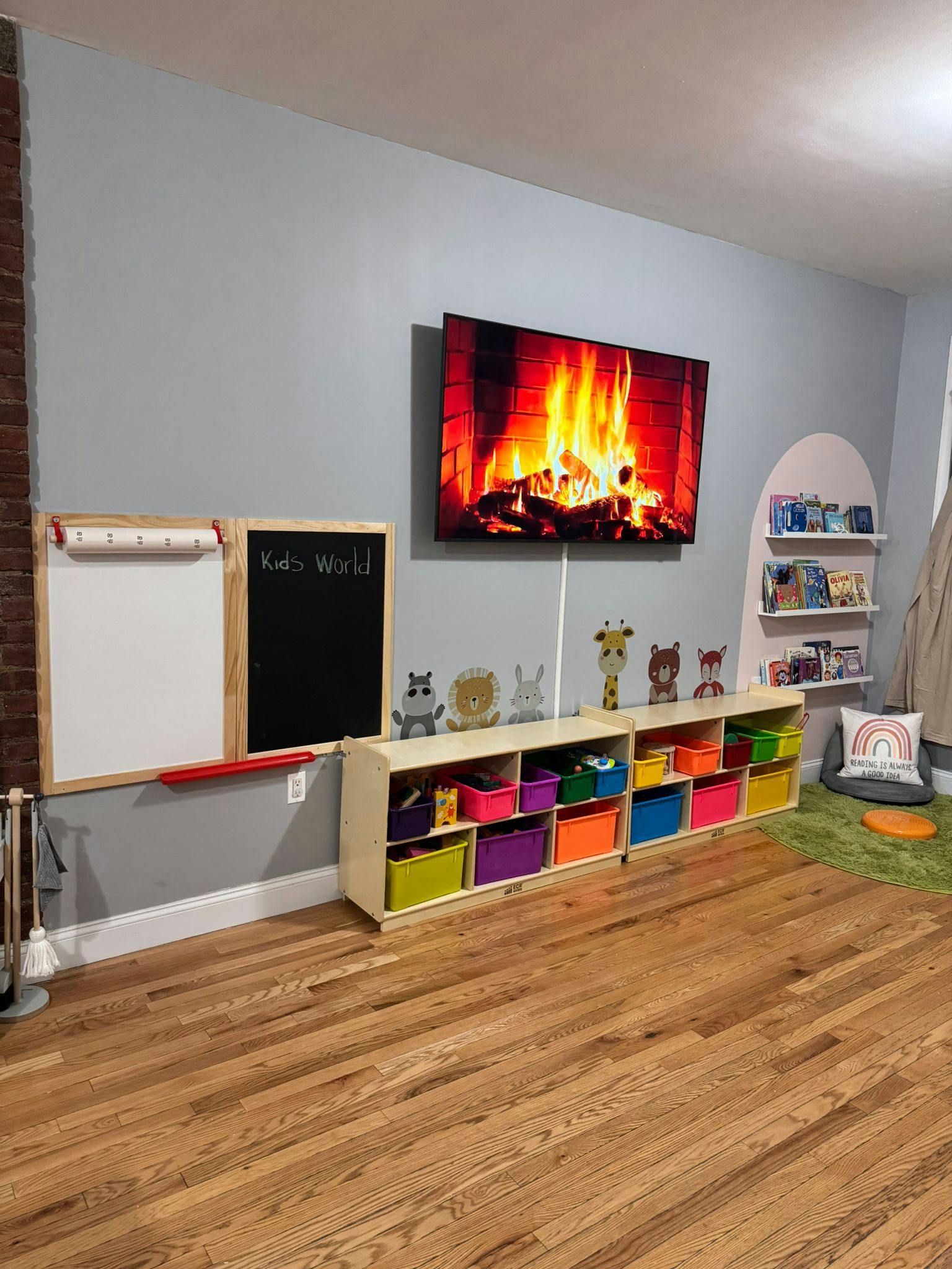 Playroom with a TV displaying a fireplace, storage bins, and a whiteboard