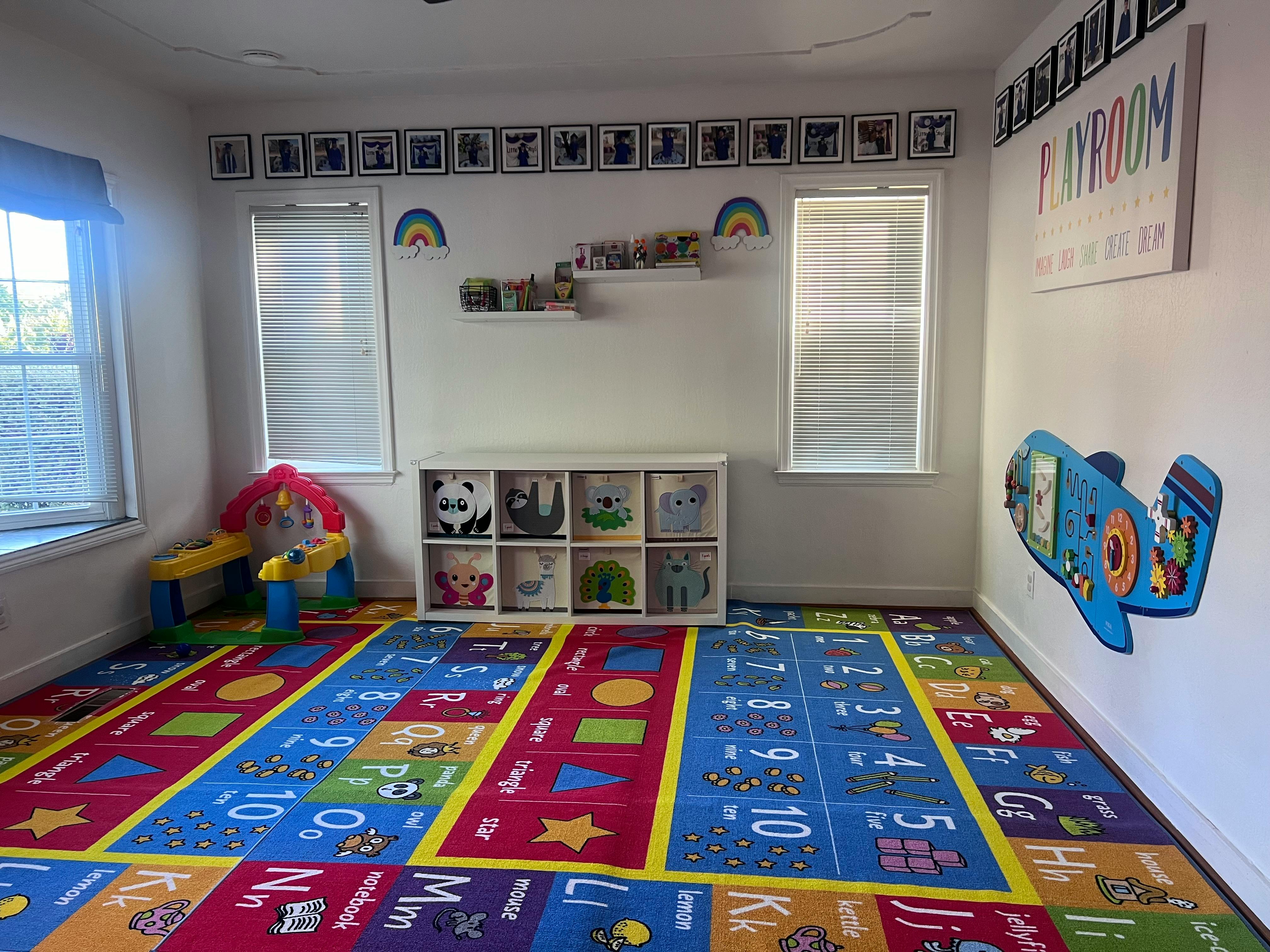 Playroom with colorful alphabet and number rug, toy storage, and wall decor