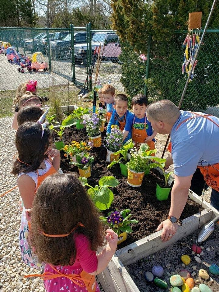 Adult and children planting flowers in a garden bed of raised garden bed