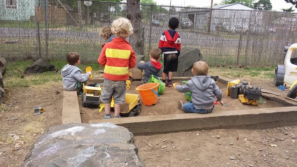 Children playing in a sandbox with toys