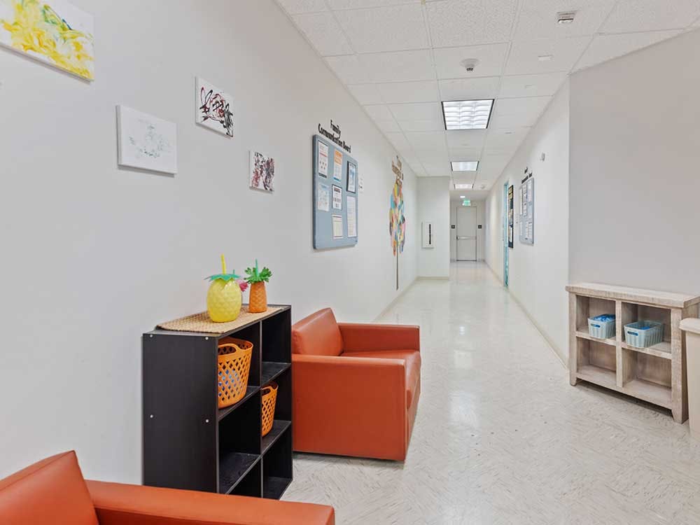 Lobby area with orange chairs, black shelves, and a long hallway