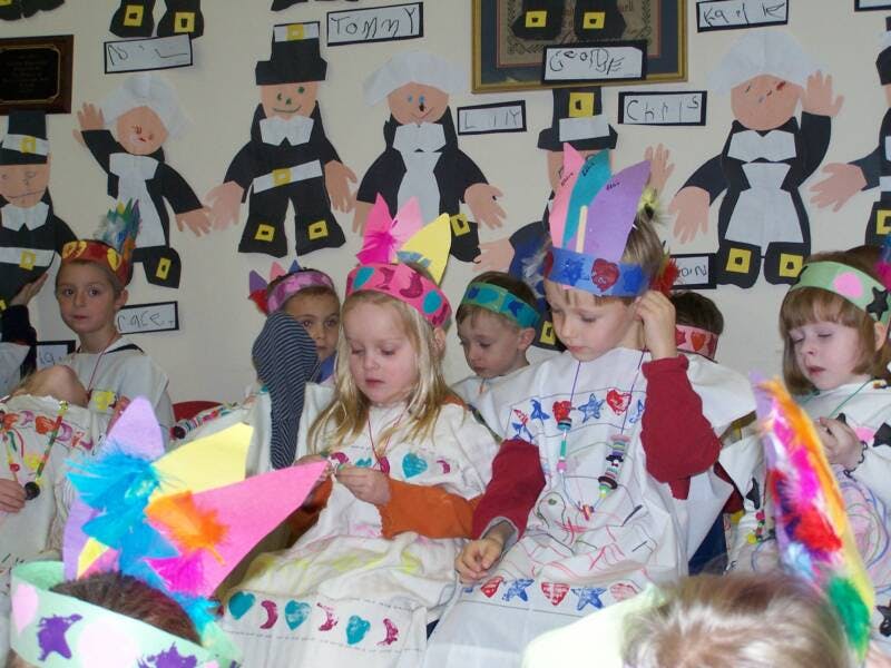 Children in colorful hats and costumes in a classroom
