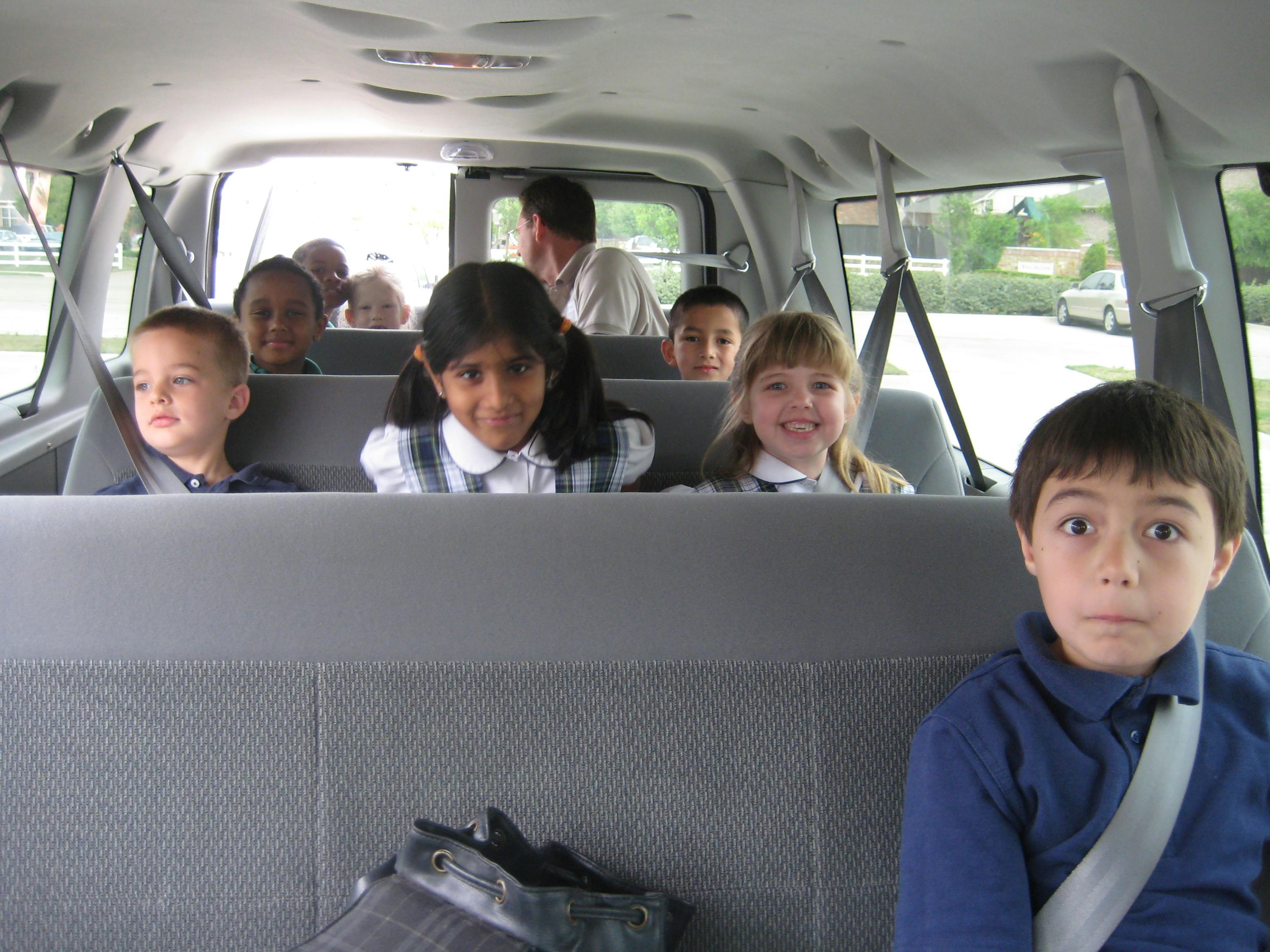 Multiple children and an adult riding in a van