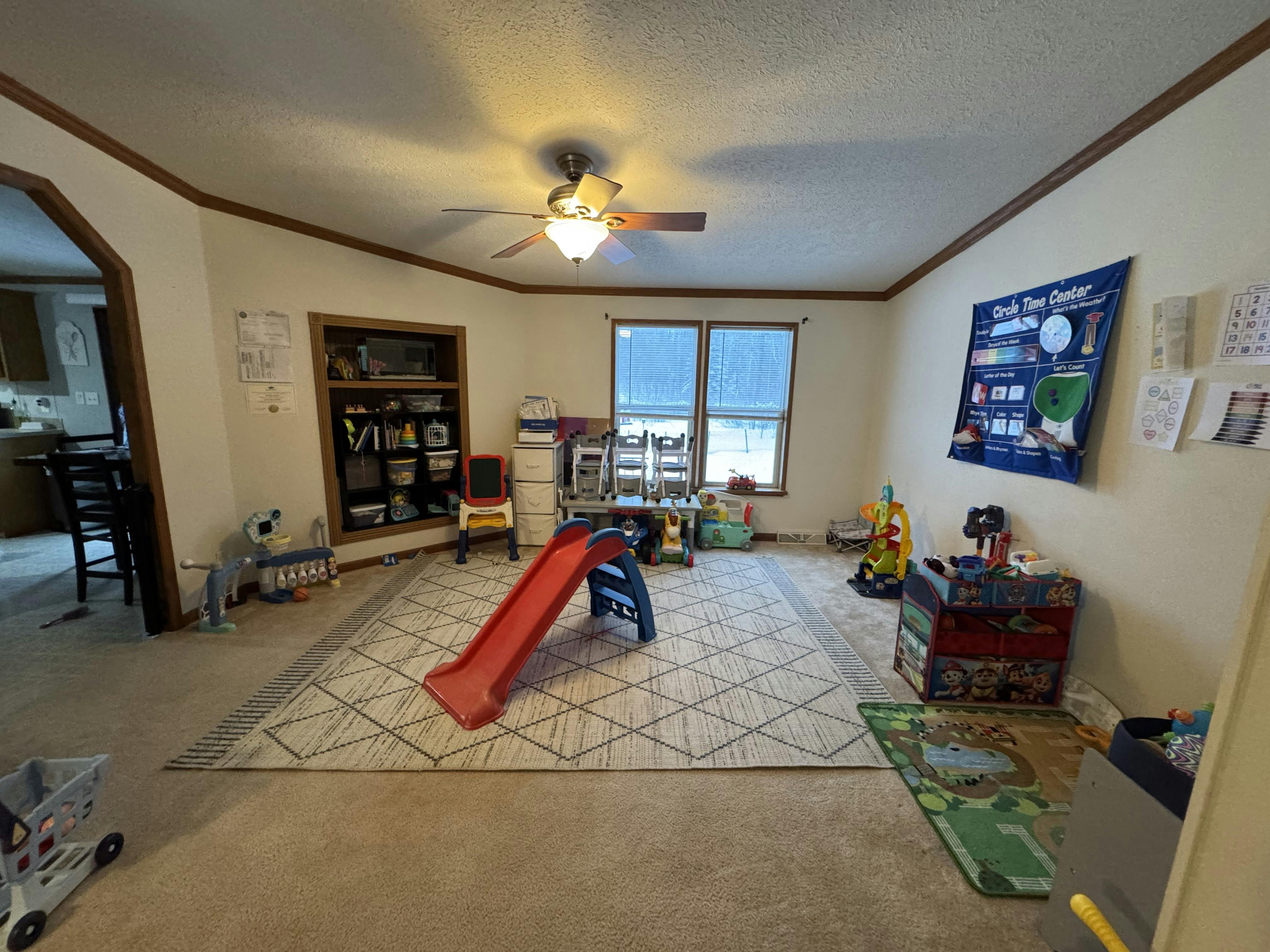 An indoor play area with a red slide, toy bins, and a 'Circle Time Center' banner