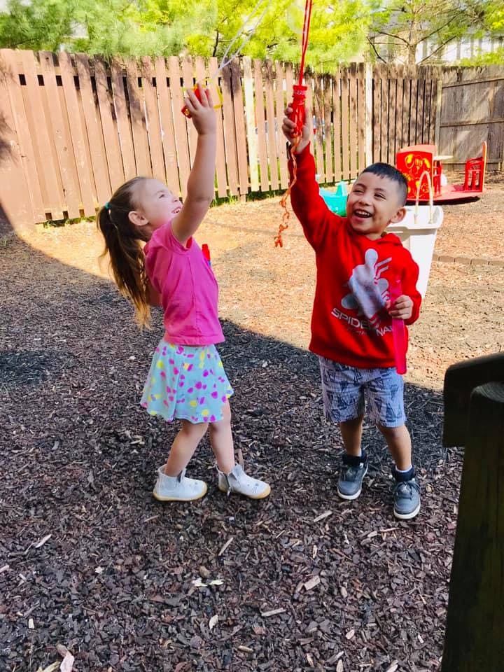 Two children playing with bubble wands outdoors