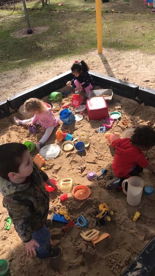 Children playing in a sandbox with toys