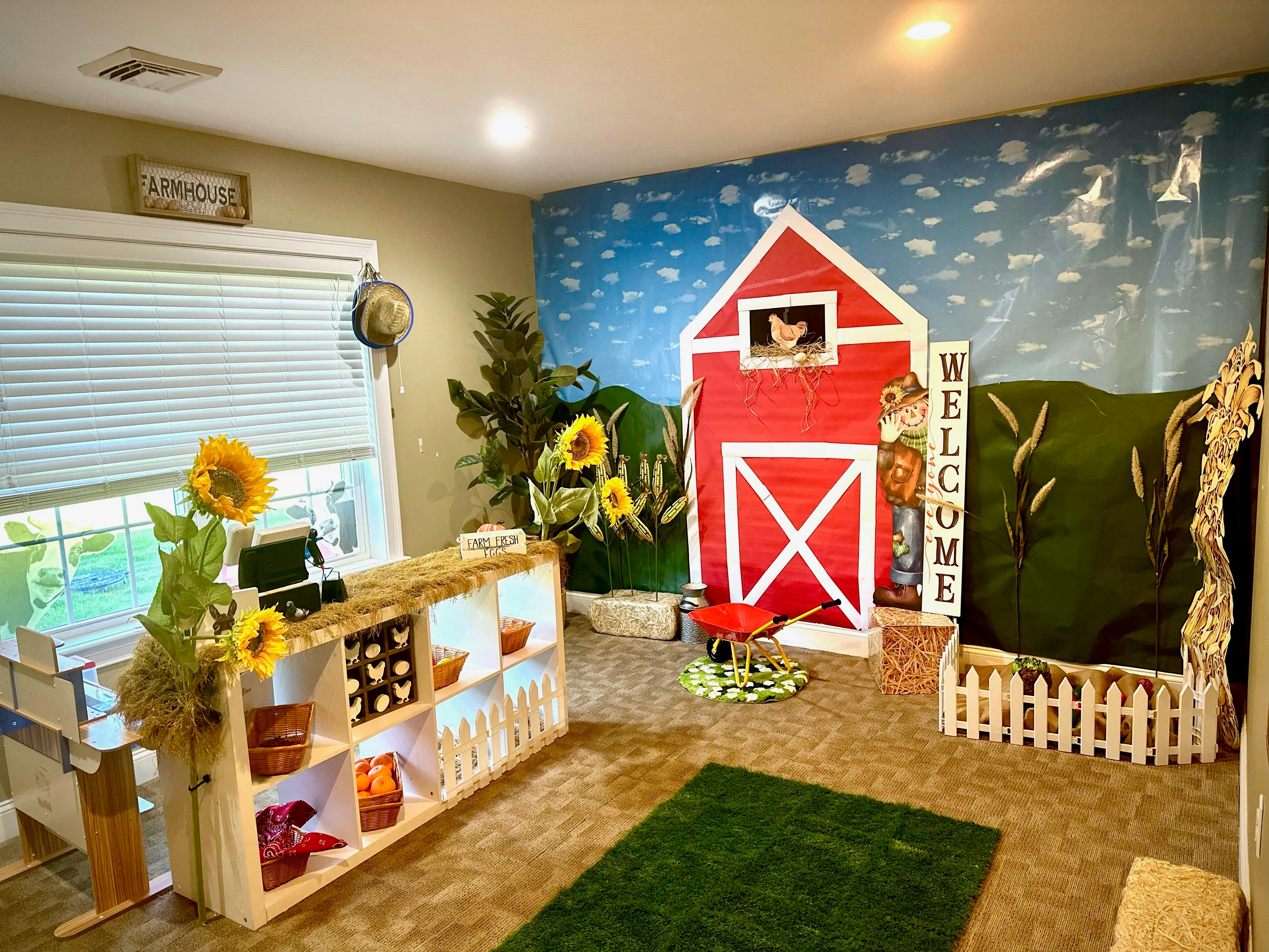 Indoor play area with farm-themed decorations including a red barn and sunflowers