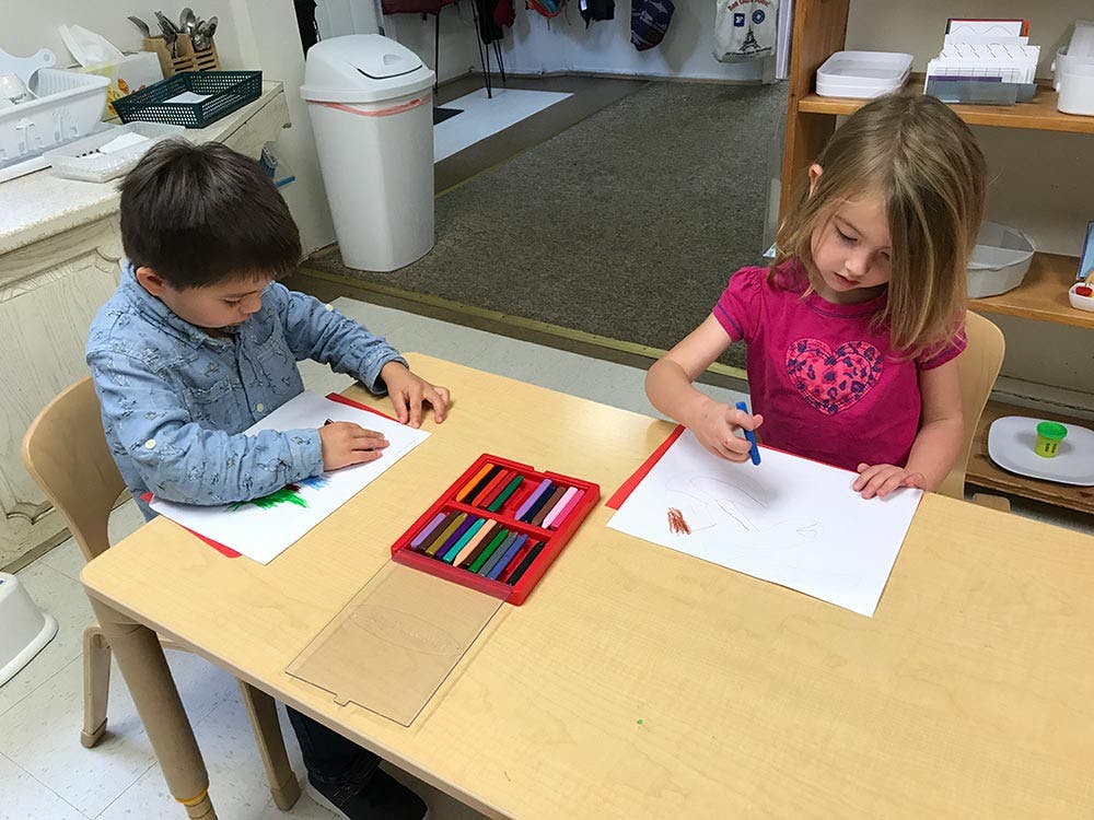 Two children drawing at a table in a classroom