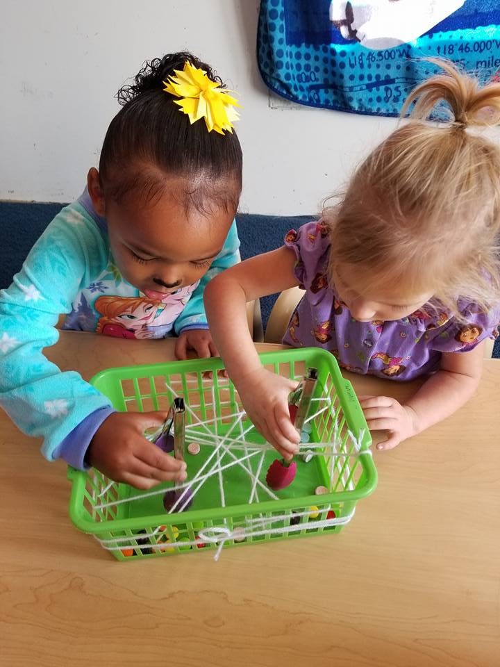 Two children playing with a green basket and string