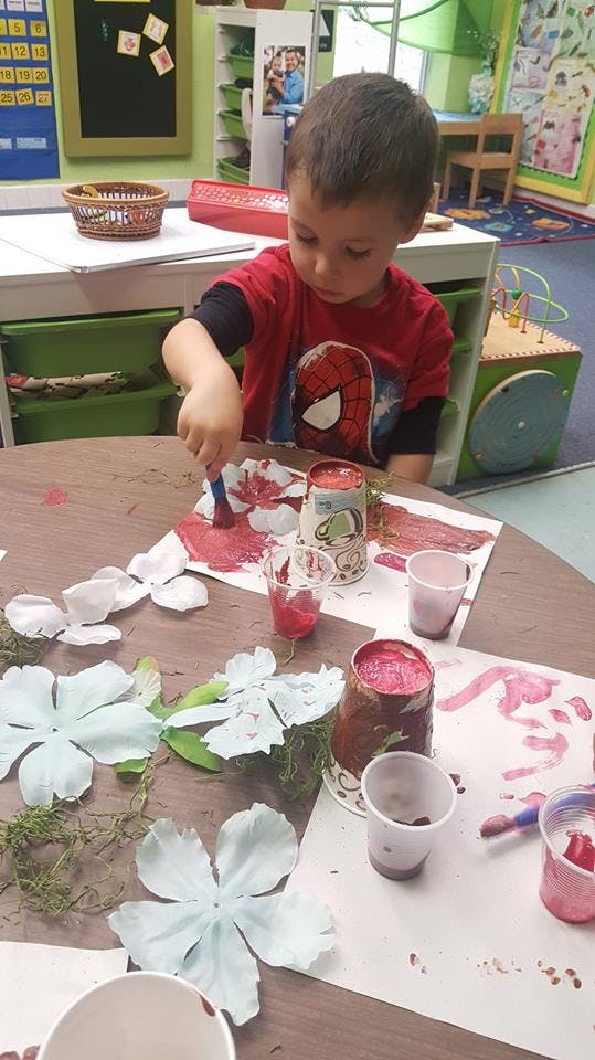 Child painting paper flowers at a table