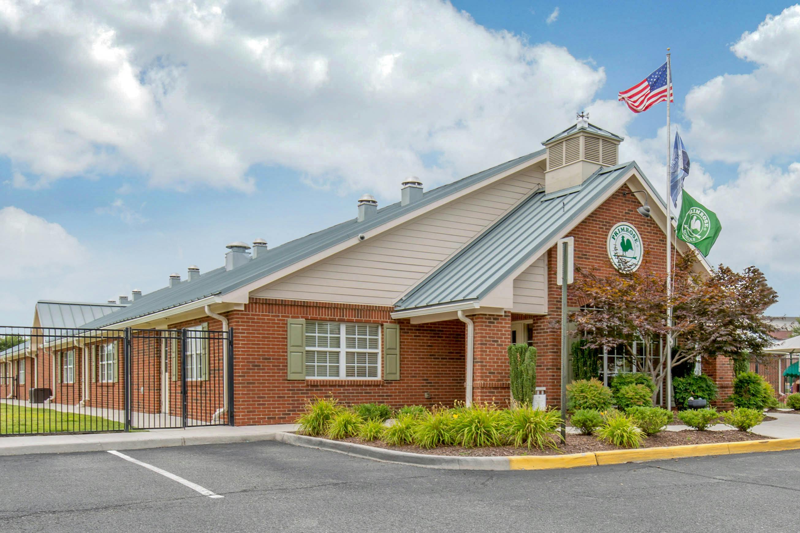 Brick building with a gray roof and two flags, one American, on poles