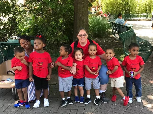 Two adults with a group of children in red shirts outdoors