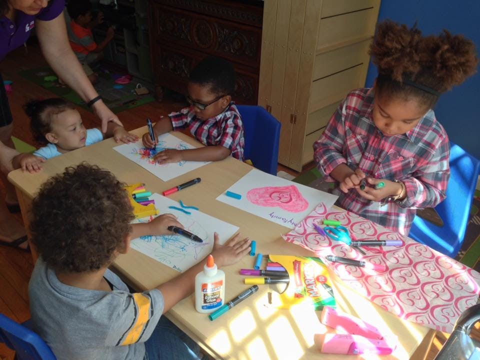 Children doing arts and crafts at a table with an adult supervising