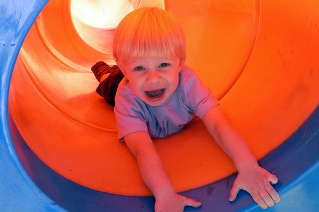 Child sliding down a tunnel slide