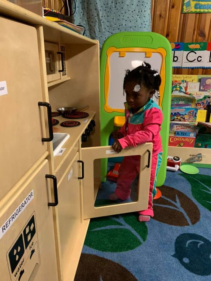 Child playing with a toy kitchen set