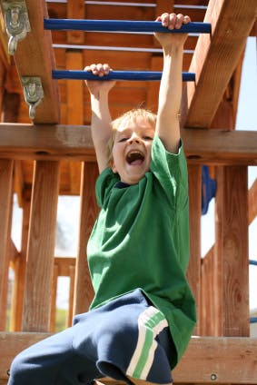 Child hanging from monkey bars on a playground