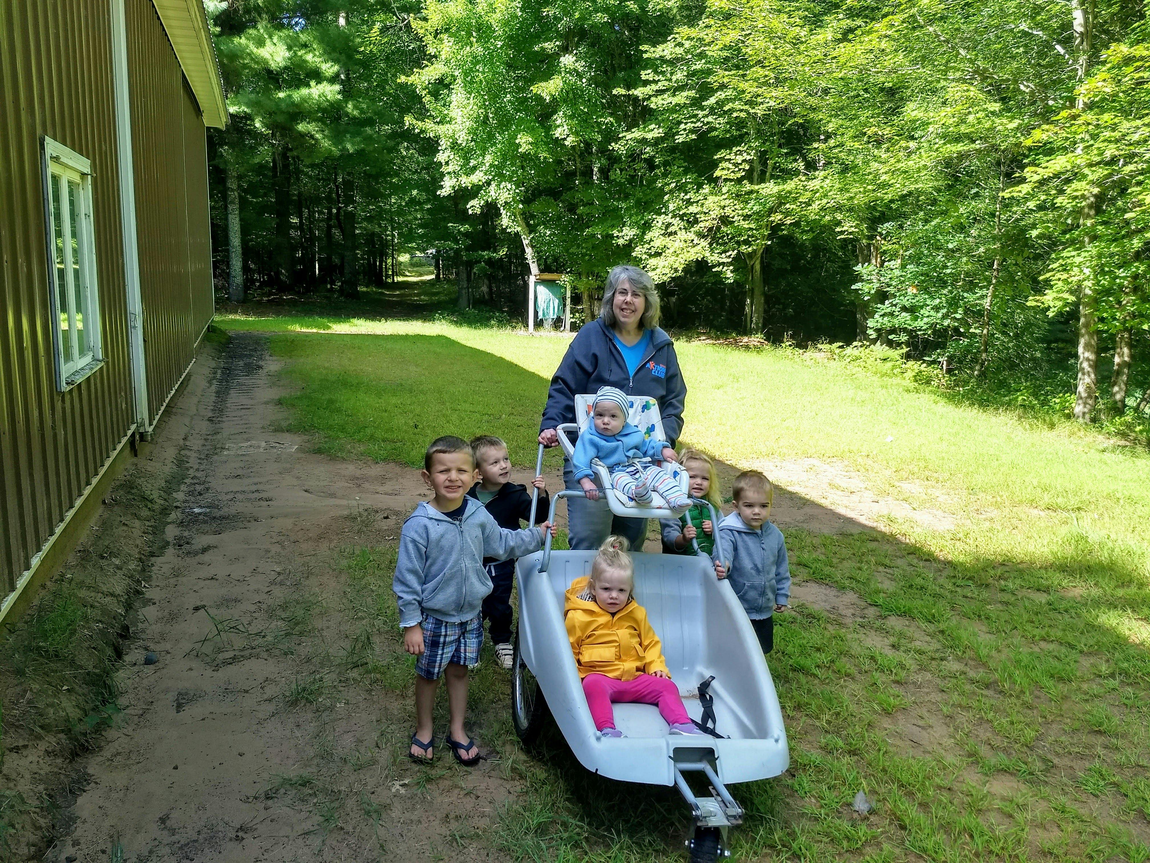 Adult and group of children with a stroller outdoors