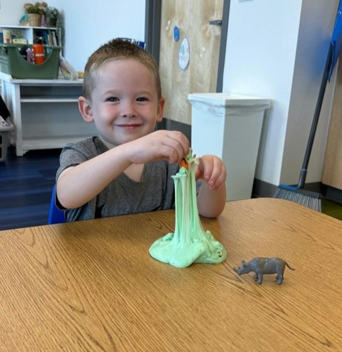 Child playing with green slime and a toy animal