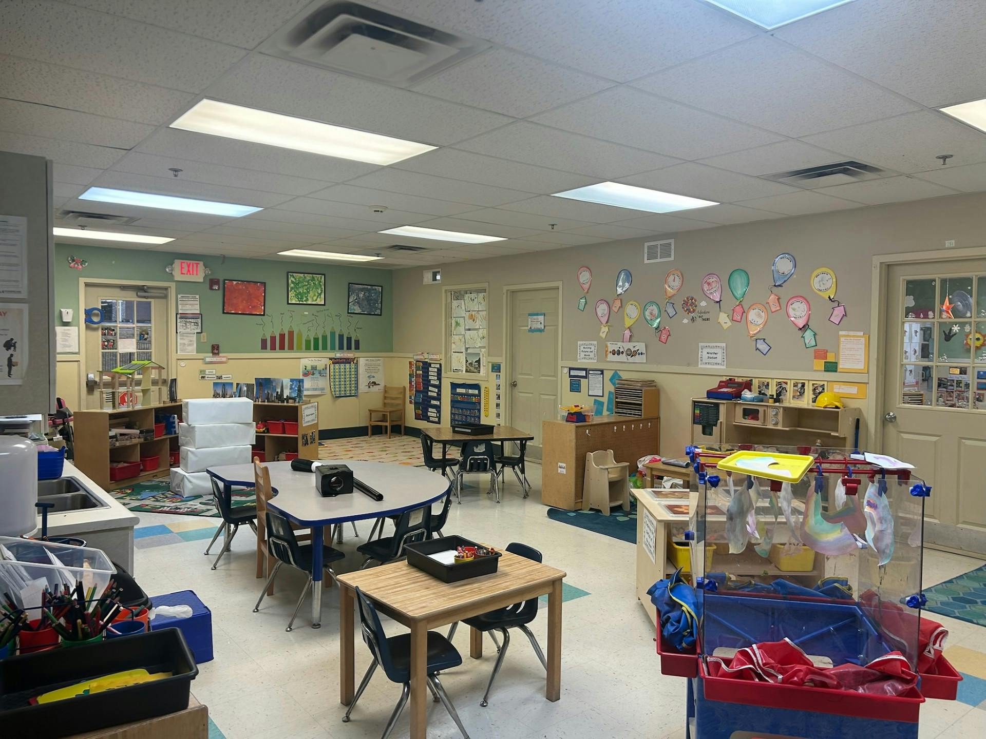 An empty classroom with small tables and chairs, and decorations on the walls