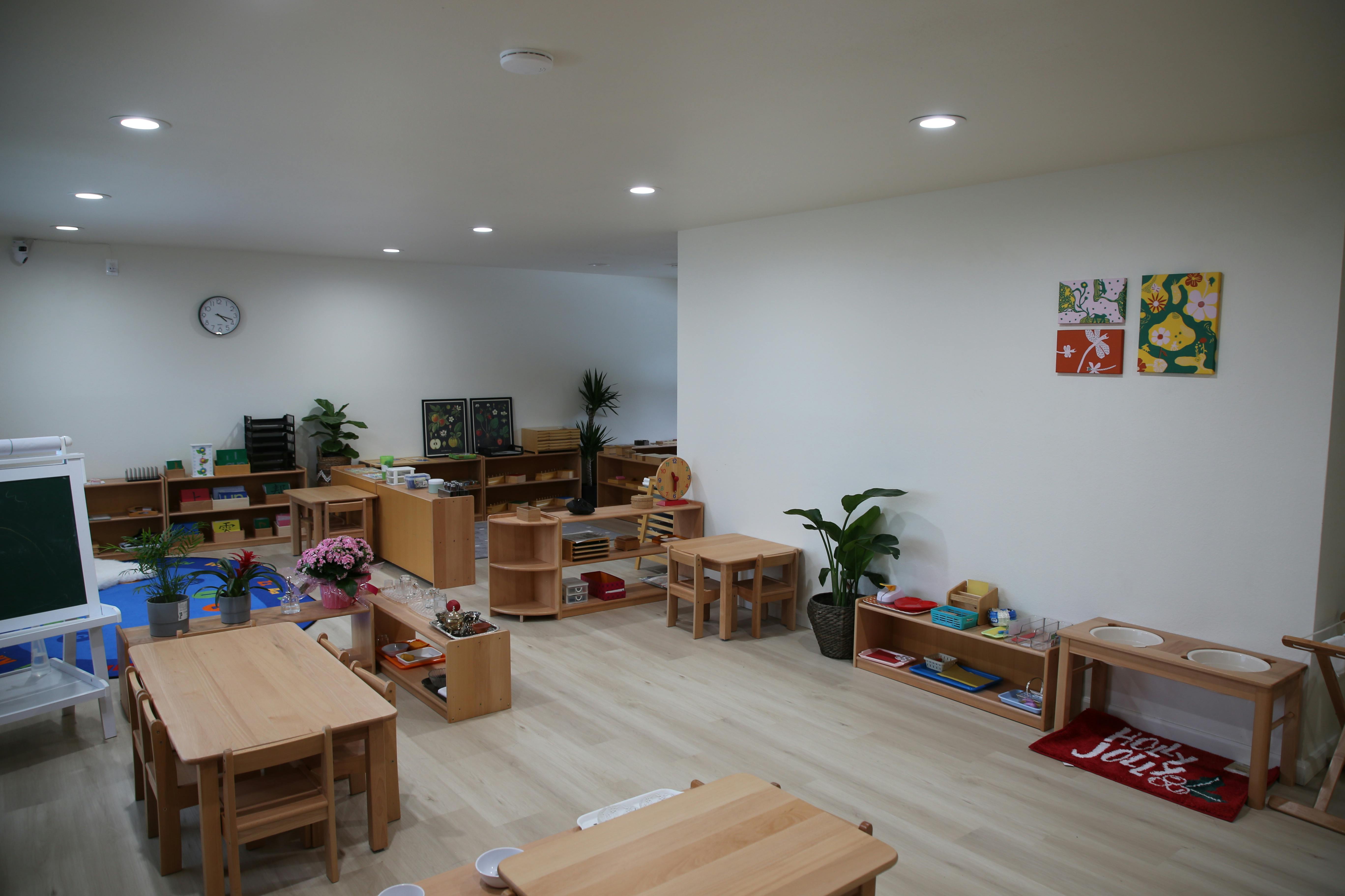 Empty classroom with small wooden tables and shelves