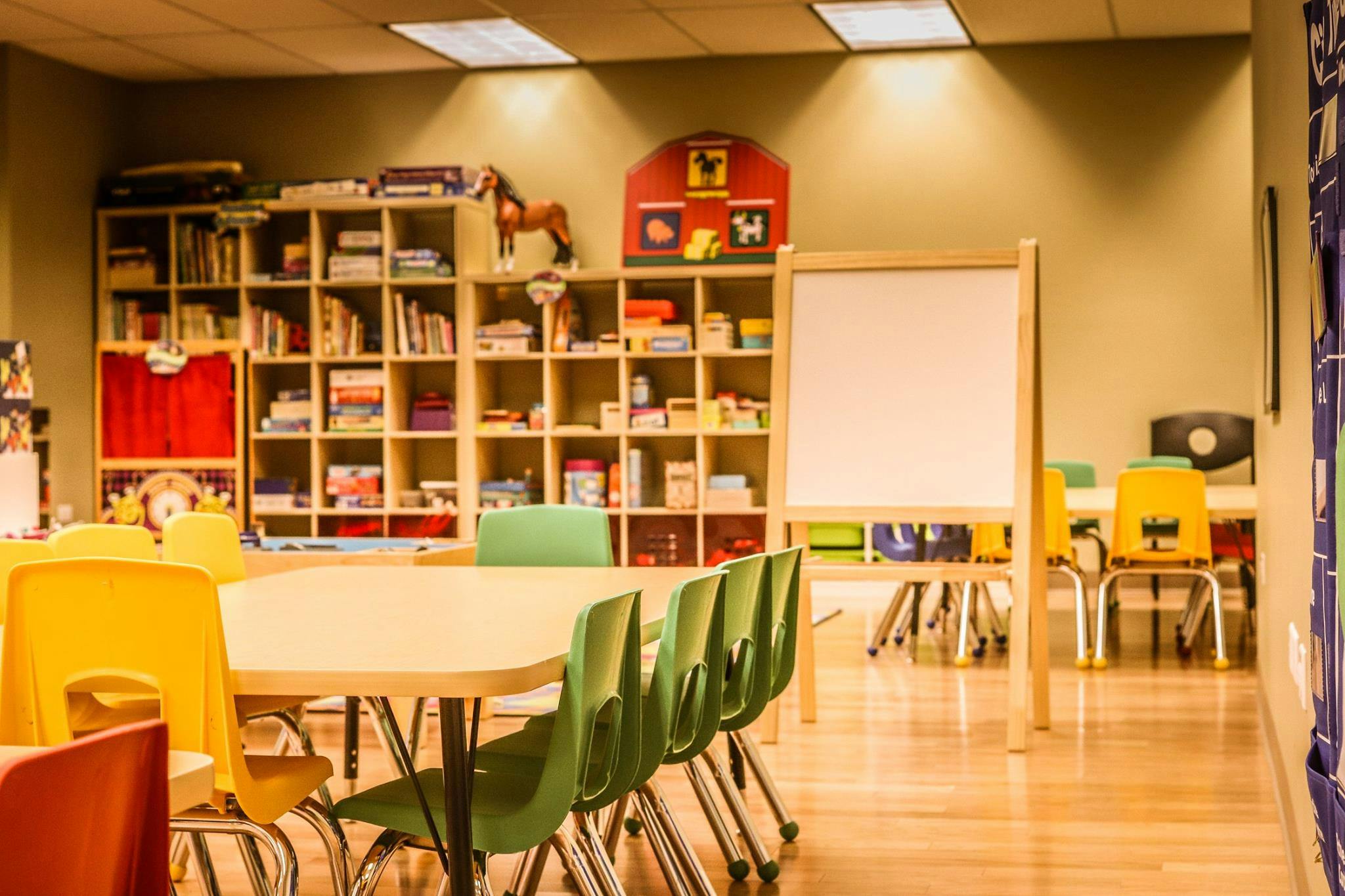 Classroom with tables, chairs, bookshelves, and a whiteboard