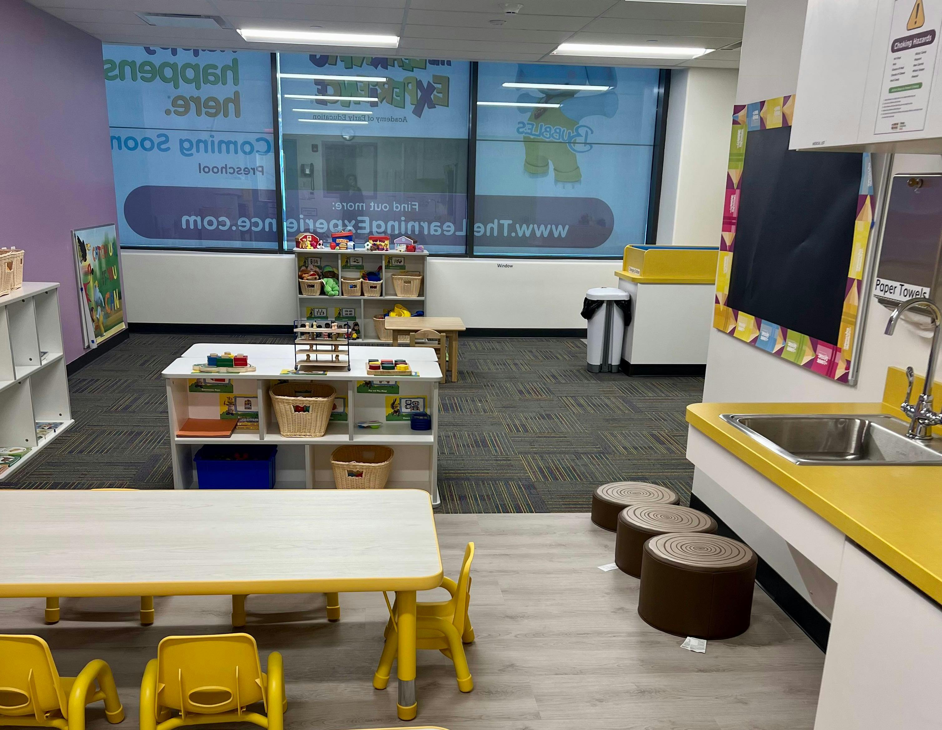 Classroom with small tables, chairs, and shelves
