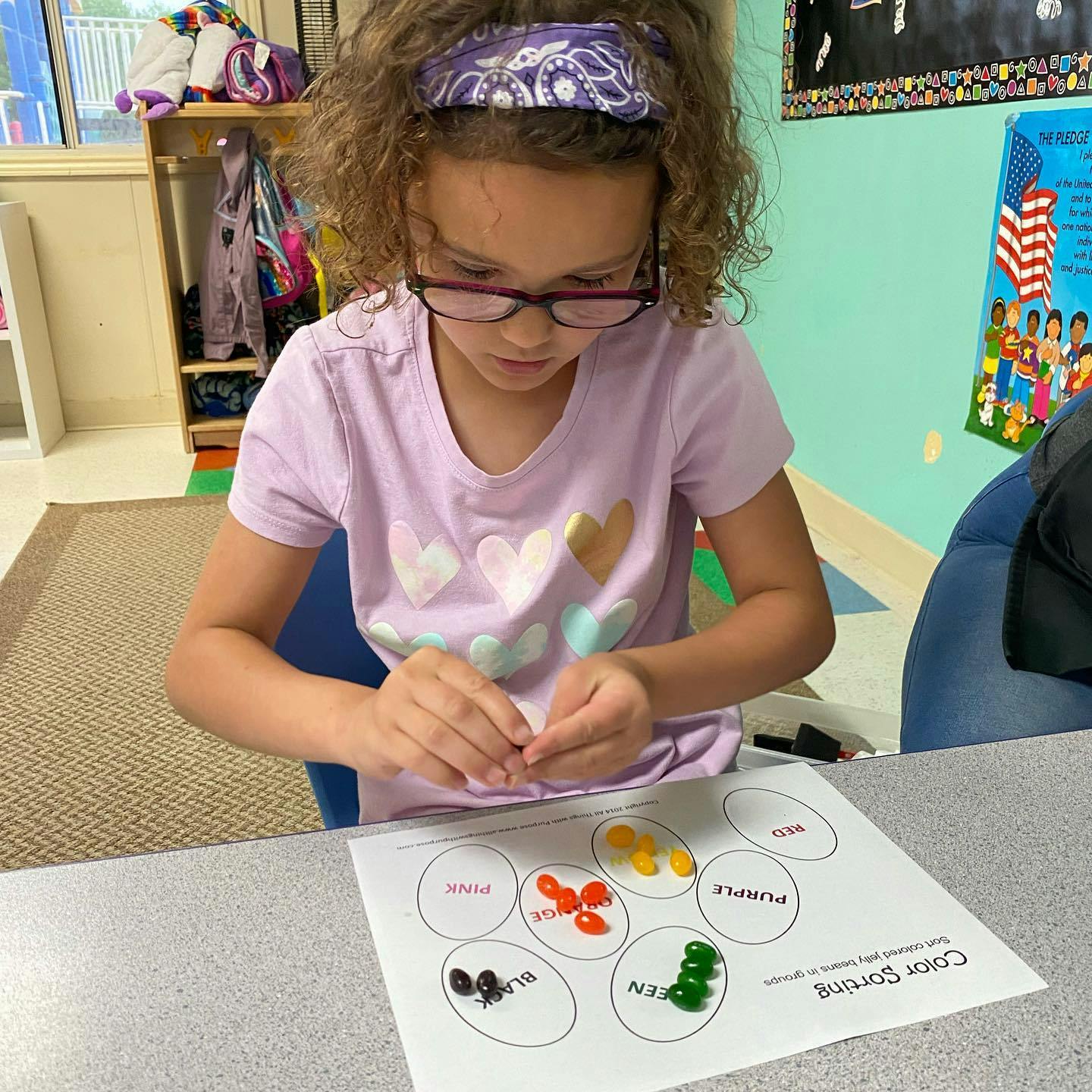Child sorting colorful objects on a paper with labeled circles
