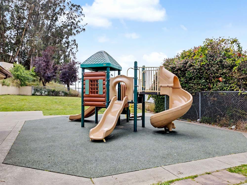 Empty outdoor playground with multiple slides on soft-fall ground