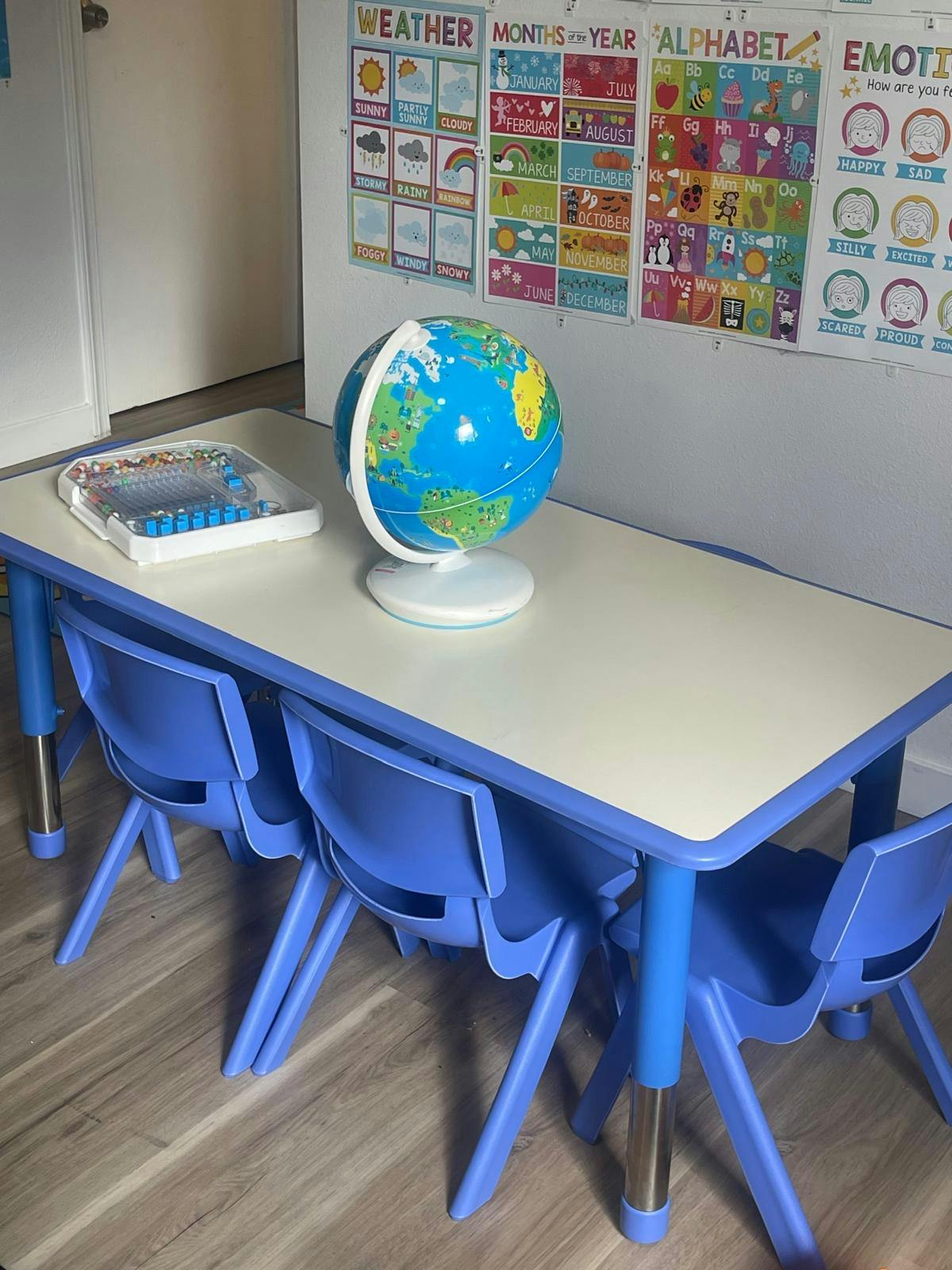 small table with blue chairs, a globe, and an educational toy, colorful mat