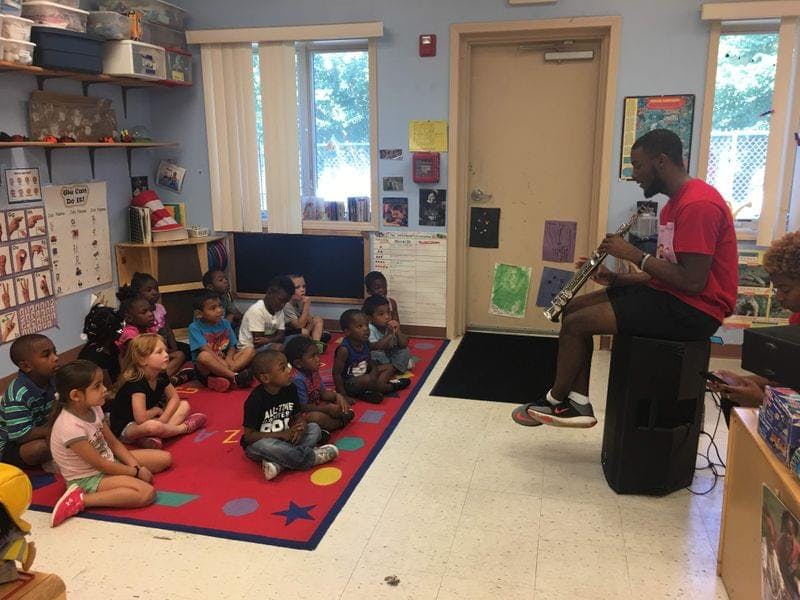 Person playing guitar for a group of children in a classroom