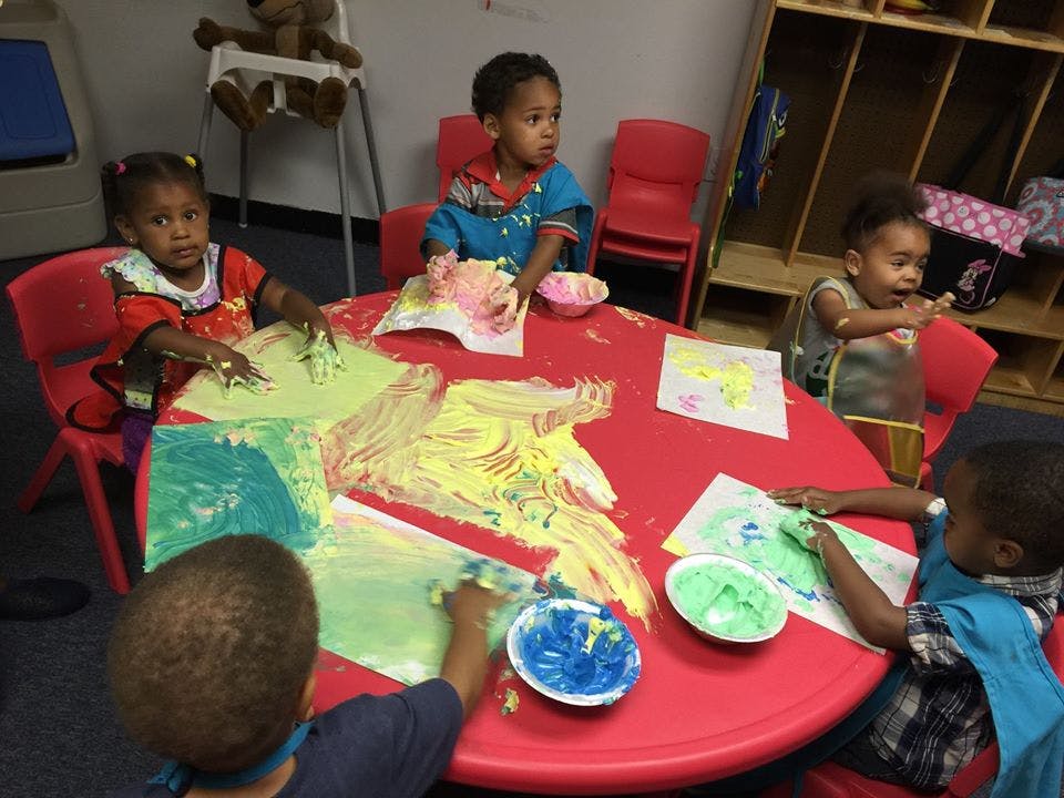 Children finger painting at a red table