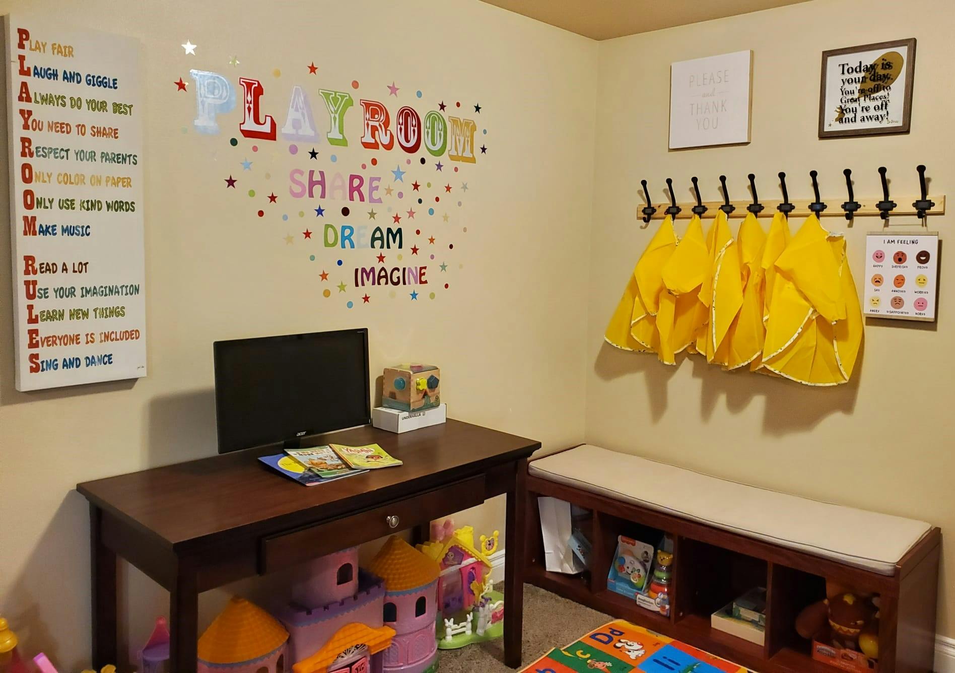 Playroom with a desk, computer monitor, and coat rack with yellow smocks