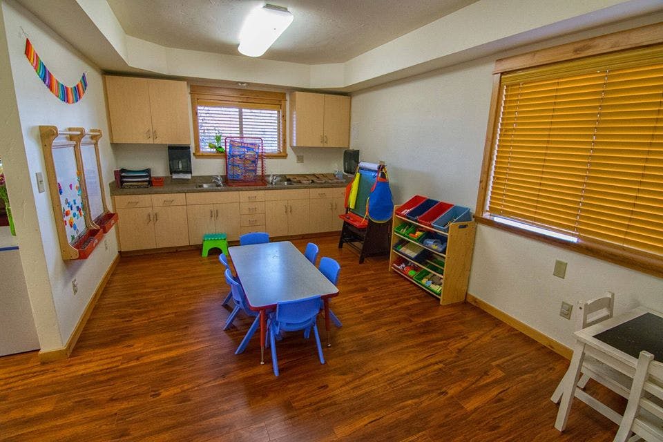 Empty classroom with small table and chairs, cabinets, and window blinds